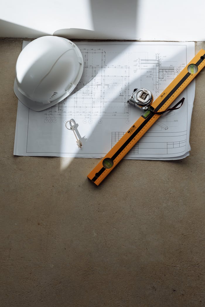 Top view of architectural blueprint with helmet and tools on table, ideal for construction theme.